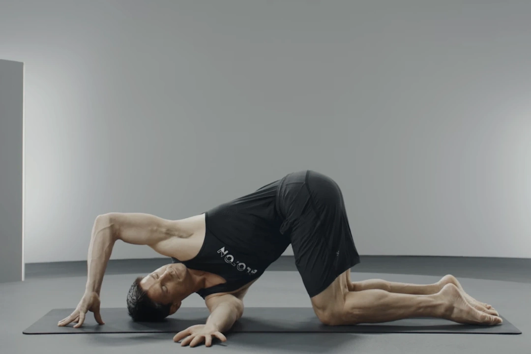 A woman doing a kneeling backbend while extending an arm out behind her.